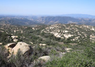 Landscape with rocks and shrubs, hills in distance